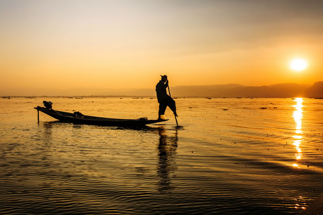A local fisherman travelling by boat on Inle lake, Myanmar.